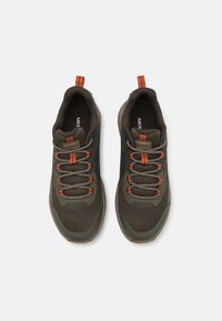 Zelené sportovní boty s texturovaným síťovinovým svrškem, oranžovými detaily a hnědými tkaničkami. Mají vyztuženou špičku a polstrovaný límec pro pohodlí.