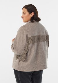 Gray felt jacket featuring a fringe detail on the back, round collar, and relaxed fit. Textured fabric enhances visual interest.
