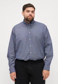 Koszula z długim rękawem, zapinana na guziki, w ciemnoniebieskim kolorze z geometrycznym wzorem, z kołnierzykiem typu point oraz logo na piersi, wykonana z mieszanki bawełny.