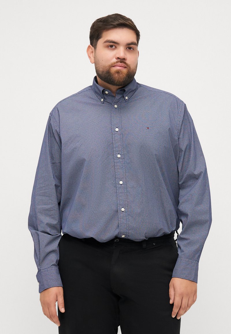Koszula z długim rękawem, zapinana na guziki, w ciemnoniebieskim kolorze z geometrycznym wzorem, z kołnierzykiem typu point oraz logo na piersi, wykonana z mieszanki bawełny.