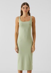 Robe bodycon vert clair en tissu lisse, avec un décolleté carré et de fines bretelles, s'étendant jusqu'à la longueur mi-mollet.