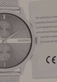 Montre à bracelet en maille argentée avec un cadran gris, trois sous-cadrans et un design bicolore. Comprend une étiquette de conformité CE sur le côté.