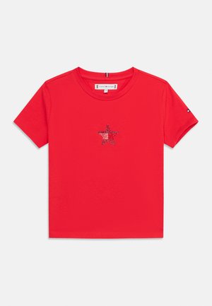 Camiseta roja de manga corta para niños pequeños con un pequeño diseño de estrella de pedrería centrado en el pecho y un detalle de logo en la manga izquierda.