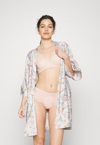 Kimono-style halja s pastelno cvetličnim vzorcem, nosi se čez čipkast modrček in usklajene čipkaste hlačke v nežnem nude odtenku. Mehka tkanina, sproščen kroj.