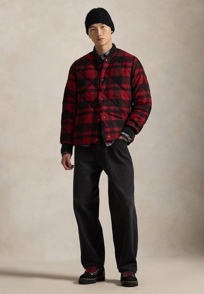 Sarkana un melna pleda raksta ar šuvēm jaka ar sprādzēm, valkāta pār tumšu kreklu un melnām biksēm. Melna adīta cepure un augsti sporta apavi ar sarkaniem šņorēm.