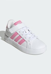 Vita sneakers med rosa detaljer, med en slät syntetisk ovandel, snörning och kardborreband, samt tre rosa ränder på sidan.