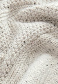 Ivory knitted fabric with a textured pattern, featuring a mix of light and dark specks. Soft, warm, and slightly bulky appearance.