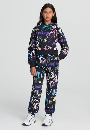 Felpa nera con cappuccio e pantaloni abbinati con motivi colorati in stile graffiti. Il materiale è morbido; il design presenta un top corto e una cintura elastica.