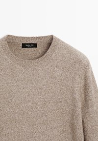 Maglione beige a maglia con collo rotondo, caratterizzato da un motivo testurizzato e un'etichetta con la scritta "Massimo Dutti" all'interno del colletto.