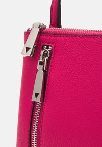 Fukssia-nahkakotelo, jossa on hopeinen varustus, kaksinkertaiset vetoketjusulkimet ja kuvioitu pinta. Kompakti muotoilu, jossa on tyylikäs siluetti.