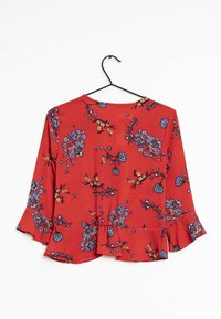 Blusa rossa a fiori con fiori blu e gialli, scollatura rotonda, maniche a tre quarti con dettagli a volant e orlo arricciato.