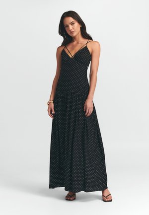 Schwarzes Maxikleid mit weißen Punkten, verstellbaren feinen Trägern, geraffter Taille und fließendem Rock für eine lässige Silhouette.