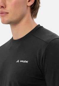 T-shirt nera realizzata in tessuto morbido, con colletto rotondo e cuciture sulle spalle discrete. Logo "VAUDE" bianco sulla parte sinistra del petto.