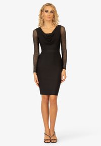 Schwarzes Kleid mit einem Schal-Ausschnitt, tailliertem Oberteil und langen durchsichtigen Ärmeln, die mit Pünktchen verziert sind. Glatte Stoffqualität, knielanges Design.