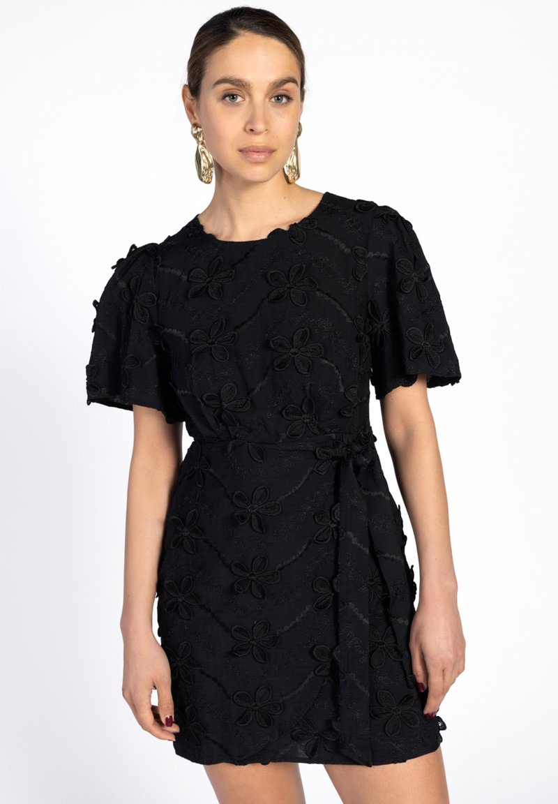 Schwarzes Kleid mit kurzen Puffärmeln, verziert mit floraler Stickerei. Es hat ein Wickeldesign und einen strukturierten Stoff.