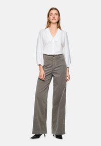 White button-up blouse with a large collar and puffed sleeves, paired with gray wide-leg corduroy pants and black pointed-toe heels.