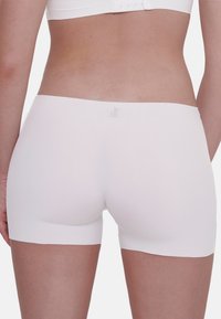 Shorts bianchi senza cuciture con una texture morbida e liscia e una vita elastica, progettati per il comfort e la facilità di movimento.