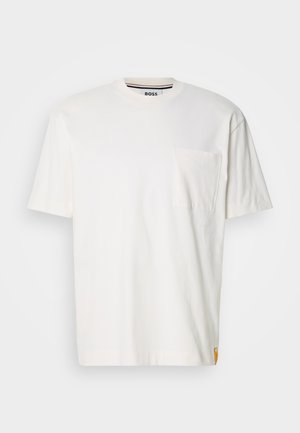 White cotton t-shirt with a round neck, short sleeves, and a left chest pocket. Features a small logo tag on the side seam.