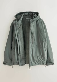 Jachetă puf verde cu glugă, interior căptușit, fermoar pe față și buzunar pe piept. Dispune de margine și mansete ajustabile pentru o potrivire confortabilă.