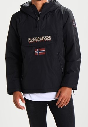 Black hooded jacket with front flap pocket featuring Napapijri logo and Norwegian flag patch, worn over a white shirt and black pants.