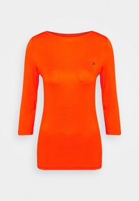 Langärmliges oranges T-Shirt aus dehnbarem Stoff, mit einem runden Ausschnitt und einem kleinen Logo-Detail auf der Brust.