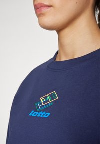 Felpa blu navy con scollo rotondo, caratterizzata da un logo geometrico multicolore e la scritta "lotto" ricamata sul petto. Materiale in cotone morbido.