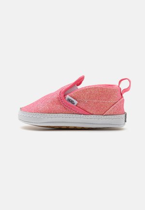 Zapato rosa para niño pequeño tipo slip-on con suela blanca, paneles laterales elásticos, lengüeta en el talón y etiqueta con el logo de Vans en el lateral.