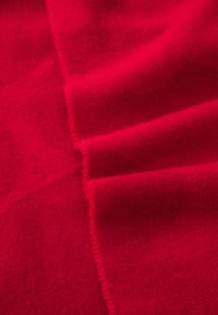 Red fabric with a soft texture, featuring folded layers that create depth. The material appears smooth and slightly fuzzy.