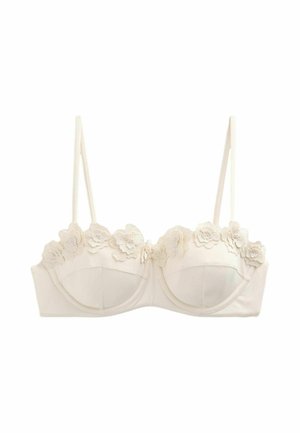 Soutien-gorge couleur crème avec armatures, fines bretelles réglables et appliques en dentelle florale le long du bord supérieur des bonnets.