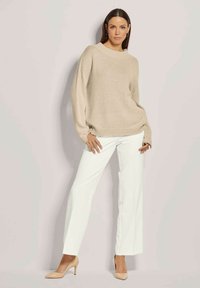 Beige gestrickter Pullover mit entspannter Passform und U-Boot-Ausschnitt, kombiniert mit hoch taillierten weißen Hosen und nude-farbenen Schuhen. Sanfte Textur und schlichtes Design.