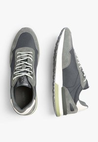 Sneakers grigi con una combinazione di suede liscio e testurizzato, lacci rotondi e una suola imbottita con un accento verde.