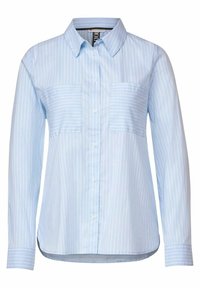 Ljusblå skjorta med knappar och vertikala vita ränder, två bröstfickor och långa ärmar. Tyget verkar slätt och lätt.