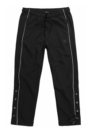 Schwarze Jogginghose mit weißer Seitenpaspel, Kordelzugbund, Druckknöpfen entlang der äußeren Beinabschlüsse und dezentem Logo am rechten Oberschenkel.