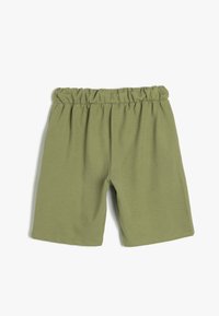Grüne Shorts mit elastischem Bund, ribbeliger Textur und einfacher, lockerer Passform auf einem schlichten weißen Hintergrund.