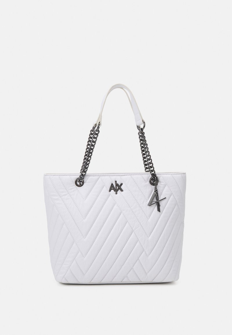 Sac cabas matelassé blanc avec motif chevrons, anses en chaîne noires avec bandoulière blanche, et logo ainsi que breloque argentés A|X à l'avant.