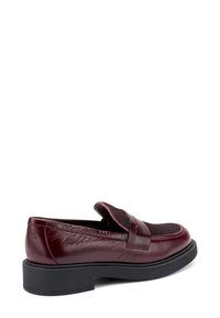 Mocassino in pelle bordeaux con punta arrotondata, dettaglio in tessuto testurizzato e suola in gomma nera, con una fascia laterale che attraversa il collo del piede.