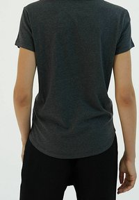 Tmavě šedé tričko s krátkým rukávem a zaobleným lemem. Měkká textura a jednoduchý design, bez viditelných grafik nebo ozdob.