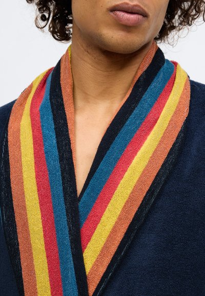 Lähedalt vaadatuna näo alumine osa ja kael, millel on seljas tumesinine rüü, millel on mitmevärviline triibuline krae, milles on kollane, punane, sinine ja oranž.