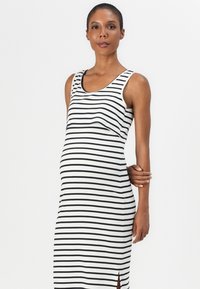 Maternity dress in a soft, ribbed fabric, featuring black and white horizontal stripes, a sleeveless design, and a side slit detail.