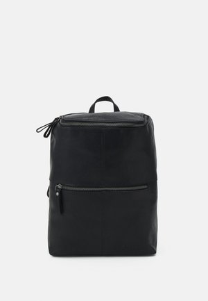 Sac à dos en cuir noir avec poignée supérieure et deux compartiments zippés, présenté sur un fond clair uni.