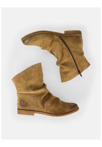 Stivali ankle in camoscio tan con design arricciato, zip laterale e suola piatta in gomma. Logo di farfalla inciso sul tallone superiore.