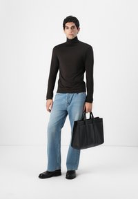 Fekete hosszú ujjú garbó, világoskék bővített szárú farmernadrág, fekete bőr tote táska, több varrással, és fekete cipők. Egyszerű, modern megjelenés.