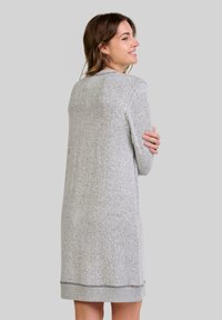 Vestido de punto gris con un corte relajado, que presenta mangas largas, un escote redondeado y un dobladillo acanalado. Textura suave con un patrón sutil.