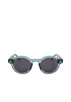 Occhiali da sole rotondi con lenti scure e montatura spessa traslucida verde-blu su sfondo bianco.