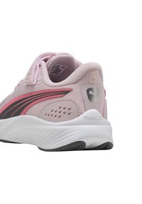 Zapatilla deportiva de color rosa claro con parte superior de tela texturizada, acentos en negro y rosa, cuello acolchado y suela blanca con trazado negro.