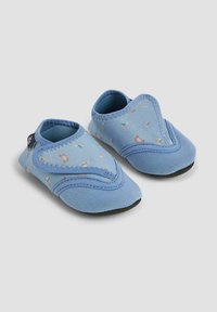 Blå tygskor för baby med mjuk sula, prydda med ett tryck av små segelbåtar och en crossover-design. Texturerad kant runt öppningarna.