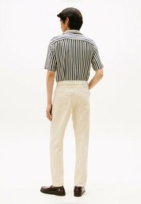 Gestreift kurzärmliges Hemd in Marineblau und Creme, kombiniert mit cremefarbenen Hosen. Maßgeschneiderte Passform mit Gesäßtaschen und glatter Stofftextur.