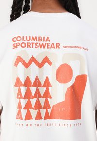 White T-shirt featuring a graphic design in orange and beige, including stylized trees, a sun, and text readings "Columbia Sportswear."