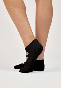 Calzini neri alla caviglia con motivo a rilievo e design a taglio. Materiale morbido con finitura liscia e banda elastica all'apertura.