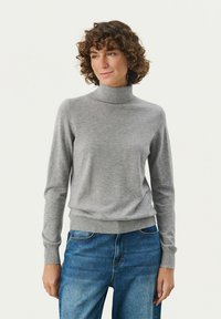 Grå turtleneck sweater lavet af blødt stof, med lange ærmer og ribbet manchetter og kant. Bæres sammen med blå denim jeans.